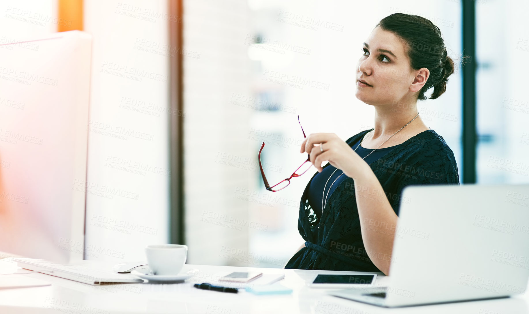 Buy stock photo Shot of a thoughtful young businesswoman working at her desk in an office