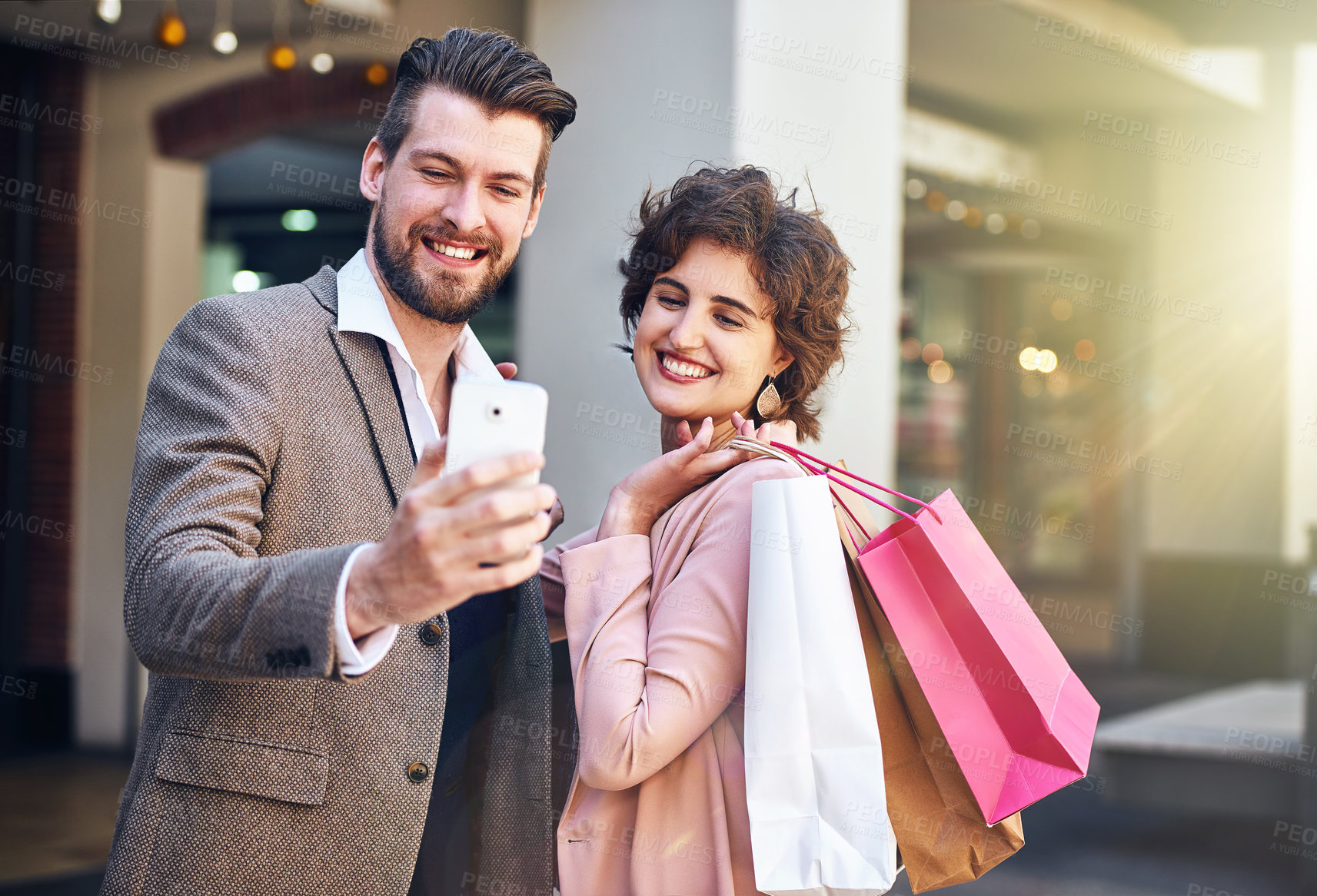 Buy stock photo Shot of a young couple taking a selfie while out shopping