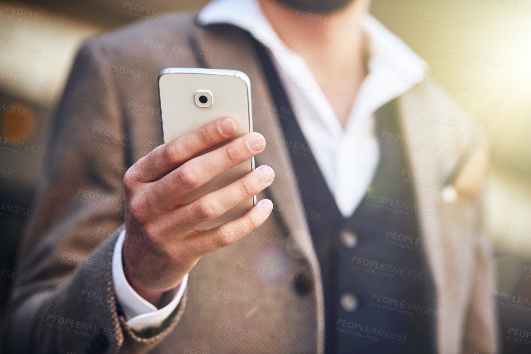 Buy stock photo Cropped shot of a young man using his cellphone while standing outside