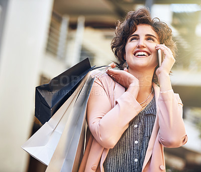 Buy stock photo Cropped shot of a young woman talking on her phone while out shopping