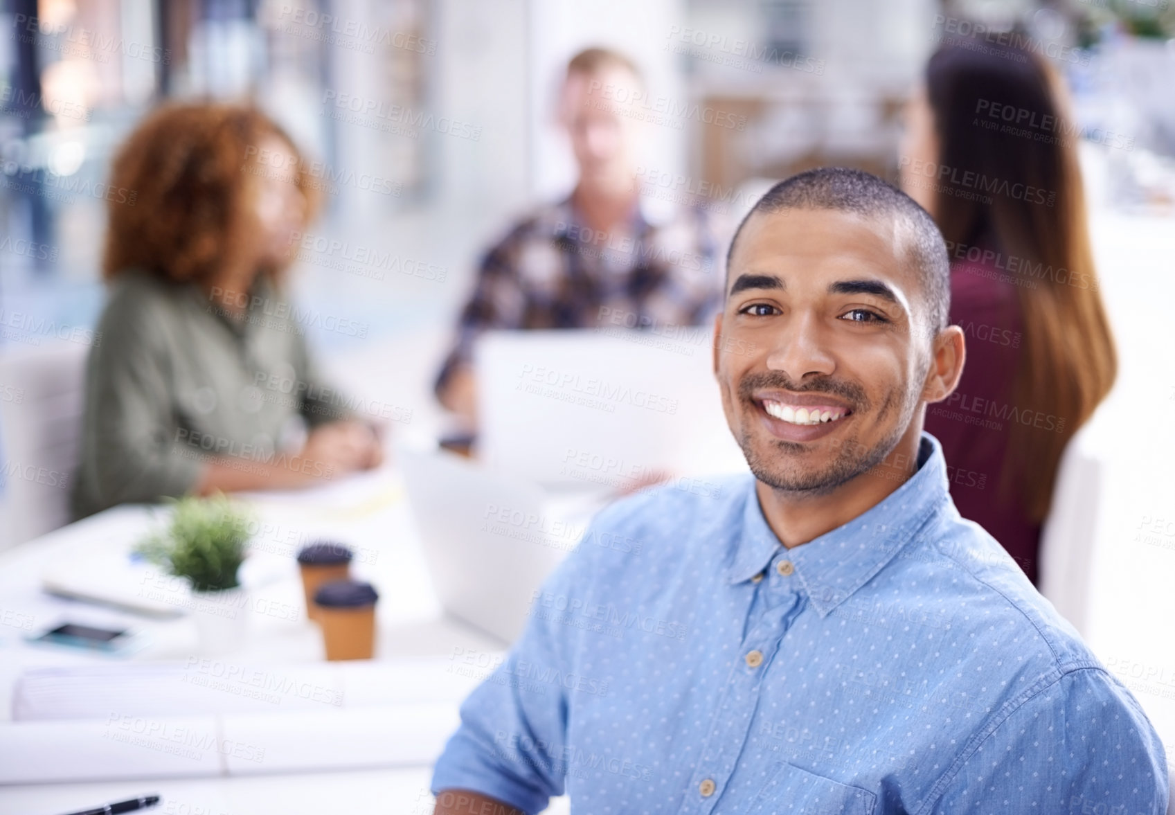 Buy stock photo Portrait of a young designer sitting in an office with his colleagues in the background