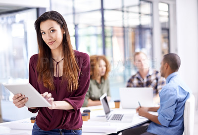 Buy stock photo Portrait of a young designer working on a digital tablet with her colleagues in the background