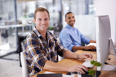 Buy stock photo Portrait of a young designer sitting in an office with his colleague in the background