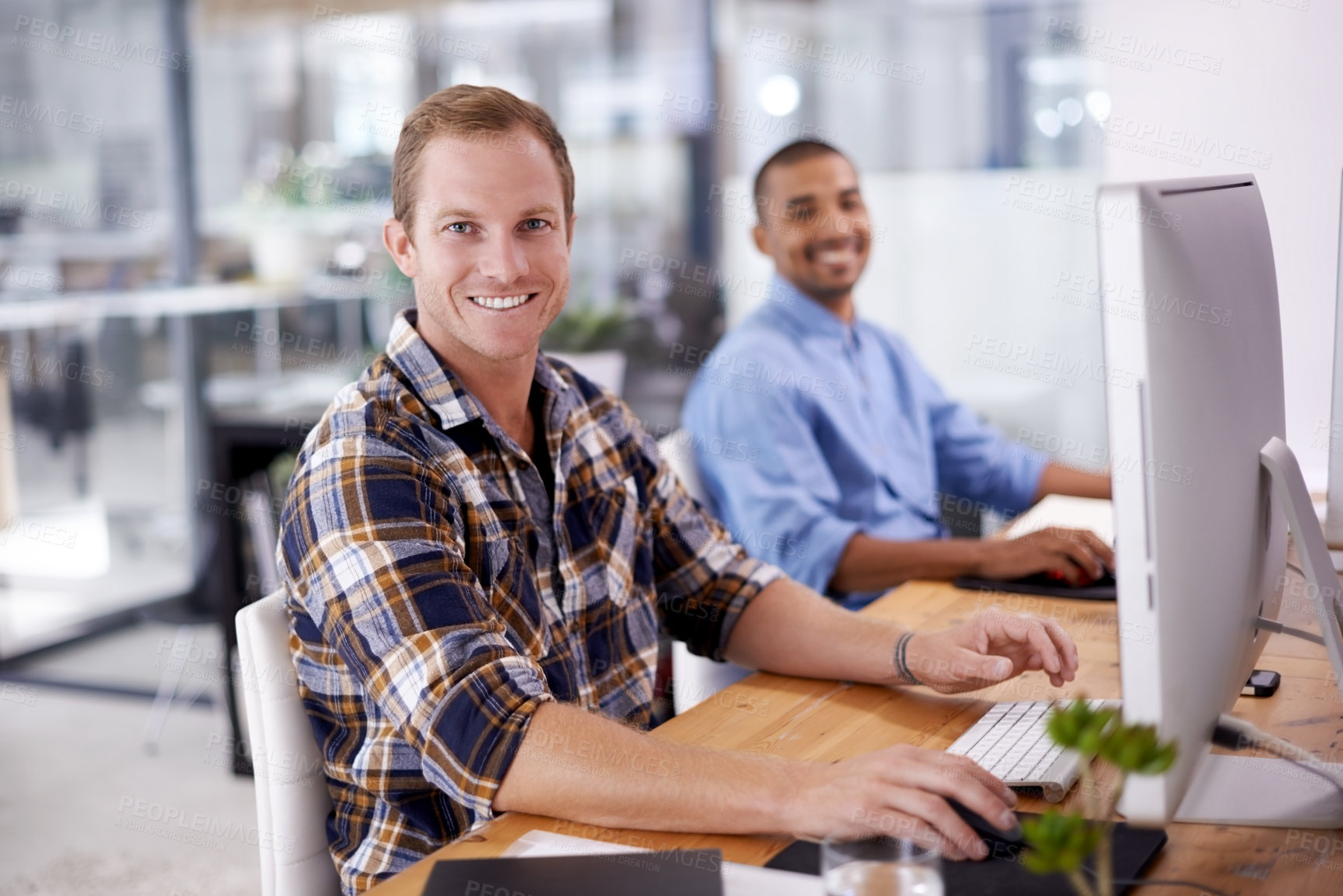 Buy stock photo Portrait of a young designer sitting in an office with his colleague in the background