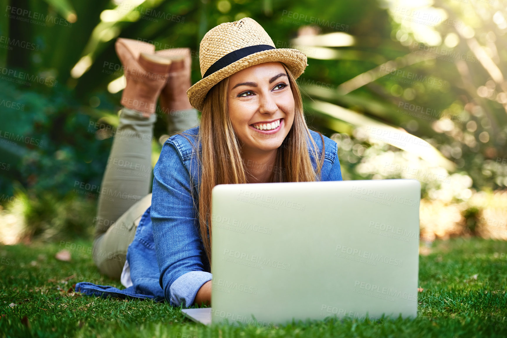 Buy stock photo Shot of an attractive young woman using her laptop while outside on the grass