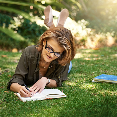Buy stock photo Shot of an attractive young woman writing in her diary while outside on the grass