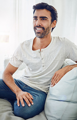 Buy stock photo Indian man, thinking and happy or relax on sofa with daydreaming, comfortable and weekend break. Person, smile and thoughtful on couch in house with wondering, inspiration and peaceful in apartment