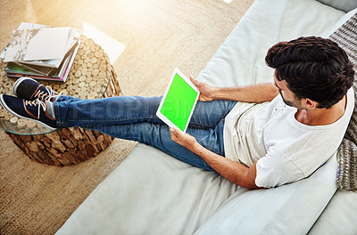 Buy stock photo Shot of a man using a digital tablet and relaxing on the sofa at home