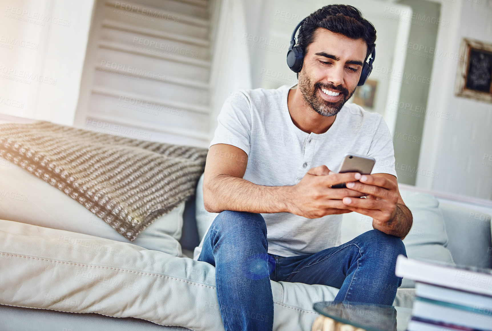 Buy stock photo Man, phone and relax with headphones on couch for music, radio search and streaming podcast in living room. Person, smartphone and happy with mobile app for listening to audio, sound or track in home