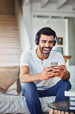 Buy stock photo Man, headphones and laughing with phone on sofa for funny video, social media post and comedy movie on mobile app. Person, smartphone and happy for listening to audio, sound and subscription in home