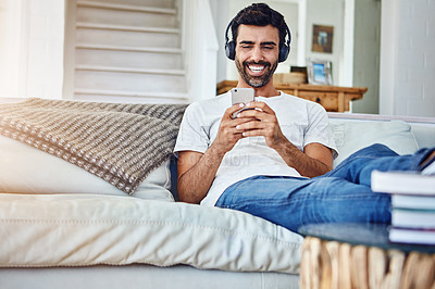 Buy stock photo Man, headphones and laughing for video in phone in home with funny social media post or comedy movie on mobile app. Person, smartphone and relax for listening to audio, sound and subscription on sofa