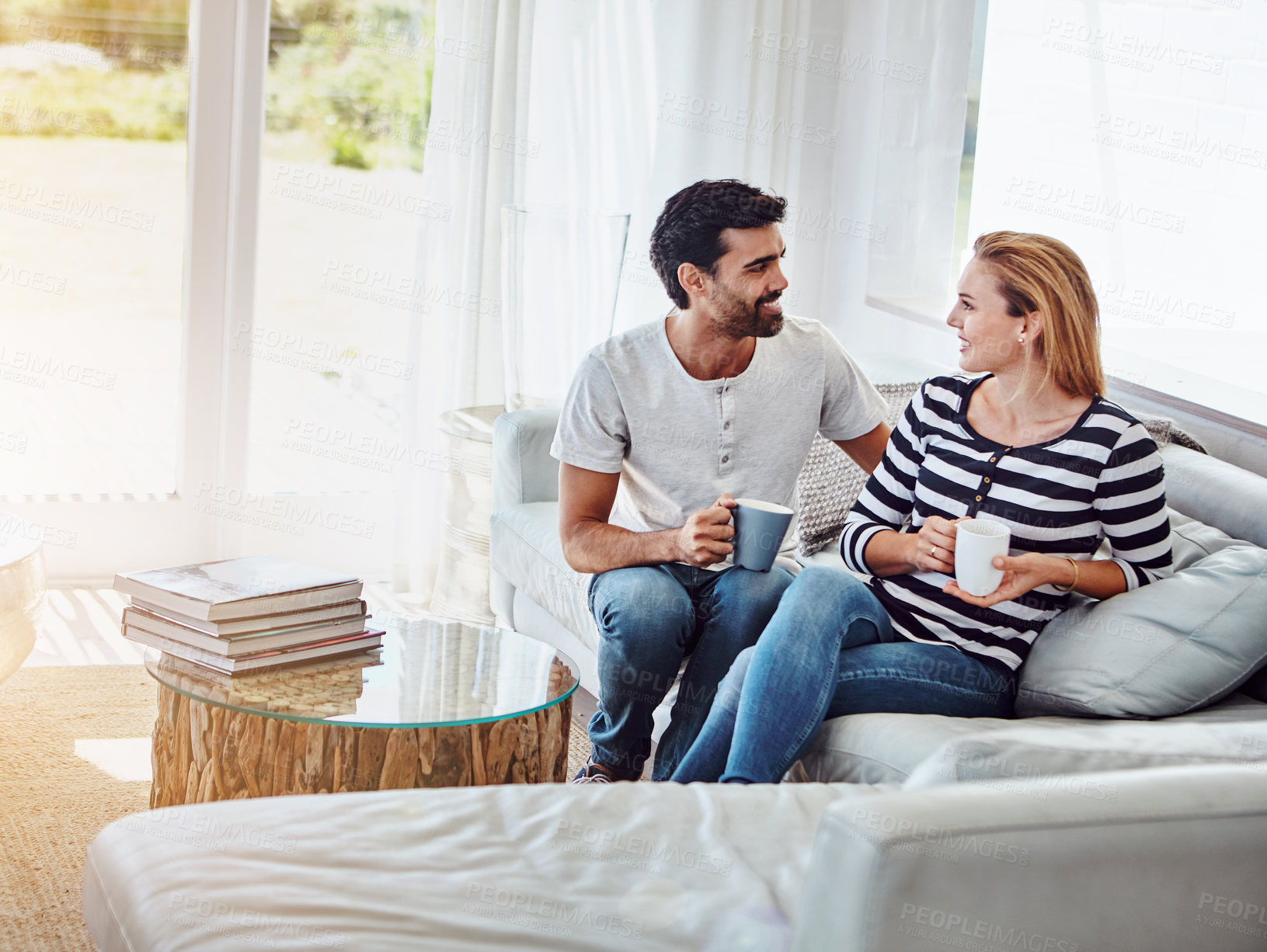 Buy stock photo Love, coffee and smile with couple on sofa for romance, bonding and support together. Calm, tea break and relationship with man and woman with mug in living room of home for marriage, drink and care