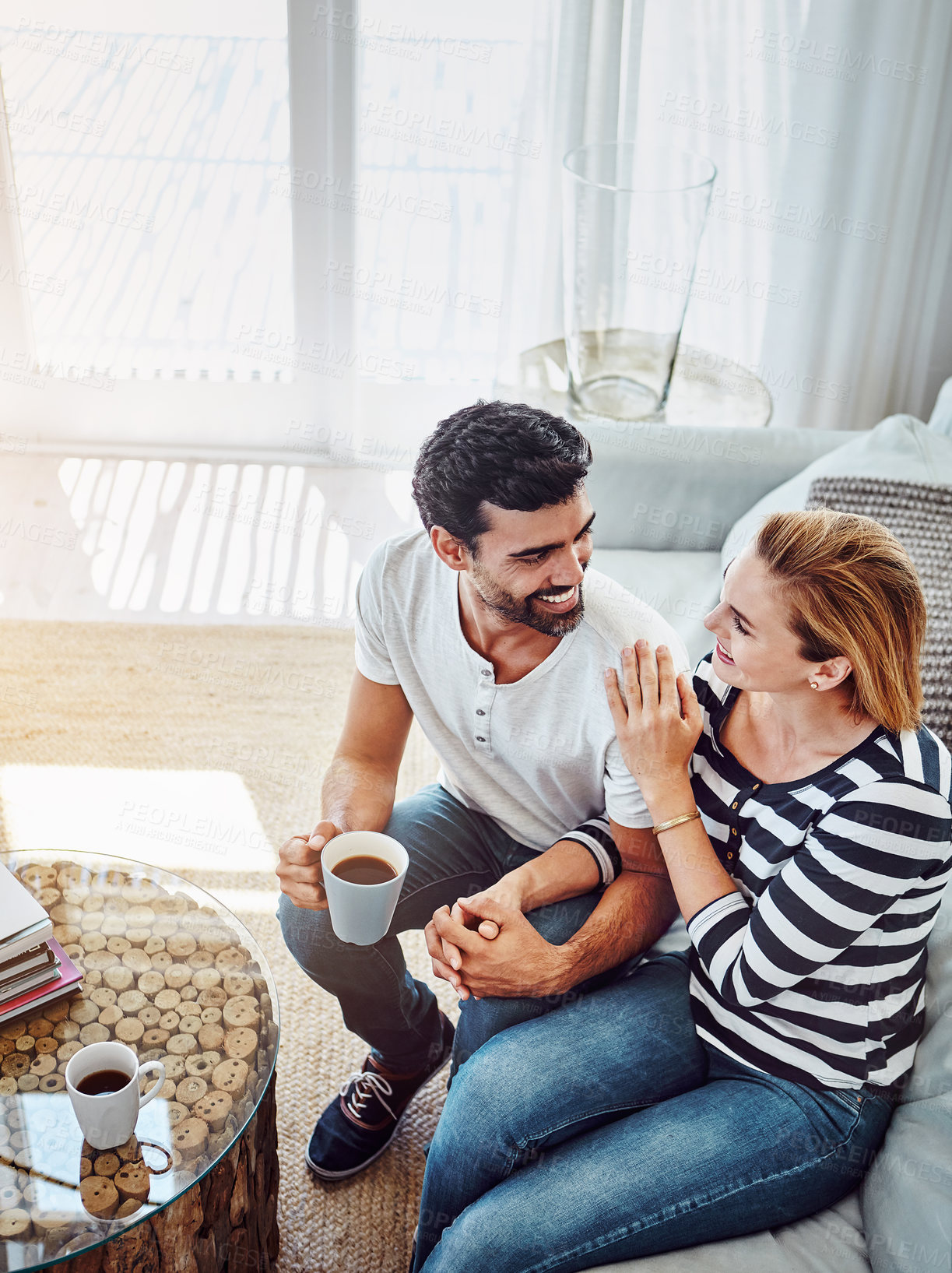 Buy stock photo High angle shot of an affectionate young couple having coffee together at home