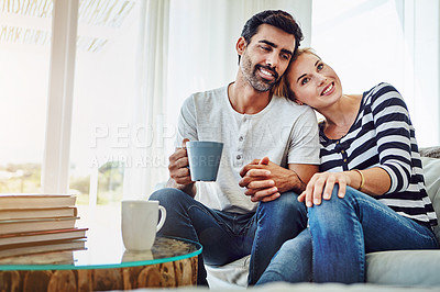 Buy stock photo Shot of an affectionate young couple having coffee while relaxing on the sofa at home