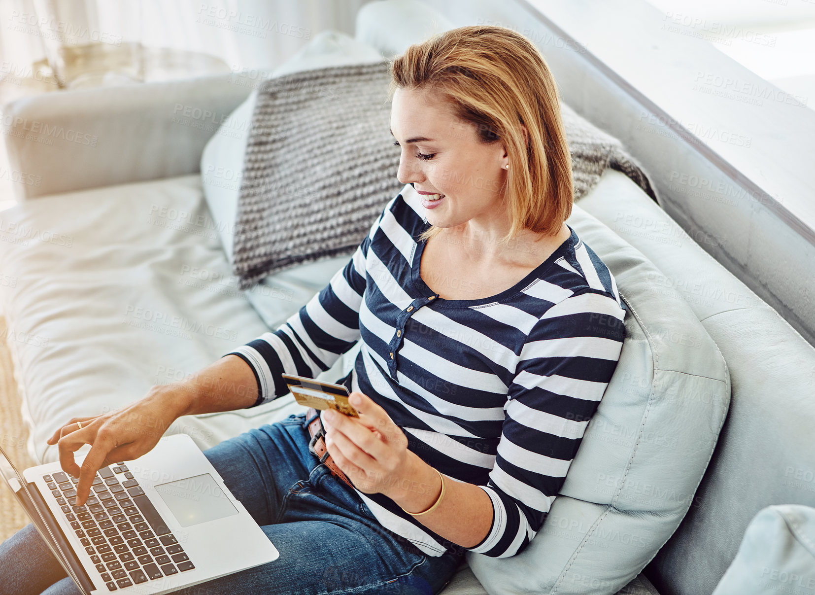 Buy stock photo High angle shot of an attractive young woman shopping online from the comfort of home