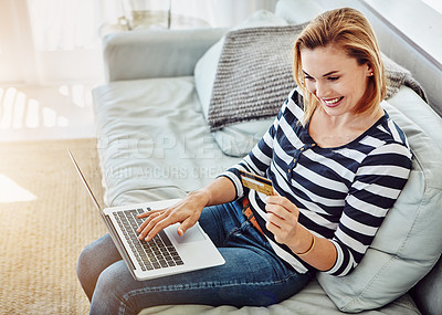 Buy stock photo High angle shot of an attractive young woman shopping online from the comfort of home