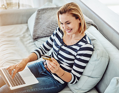 Buy stock photo High angle shot of an attractive young woman shopping online from the comfort of home