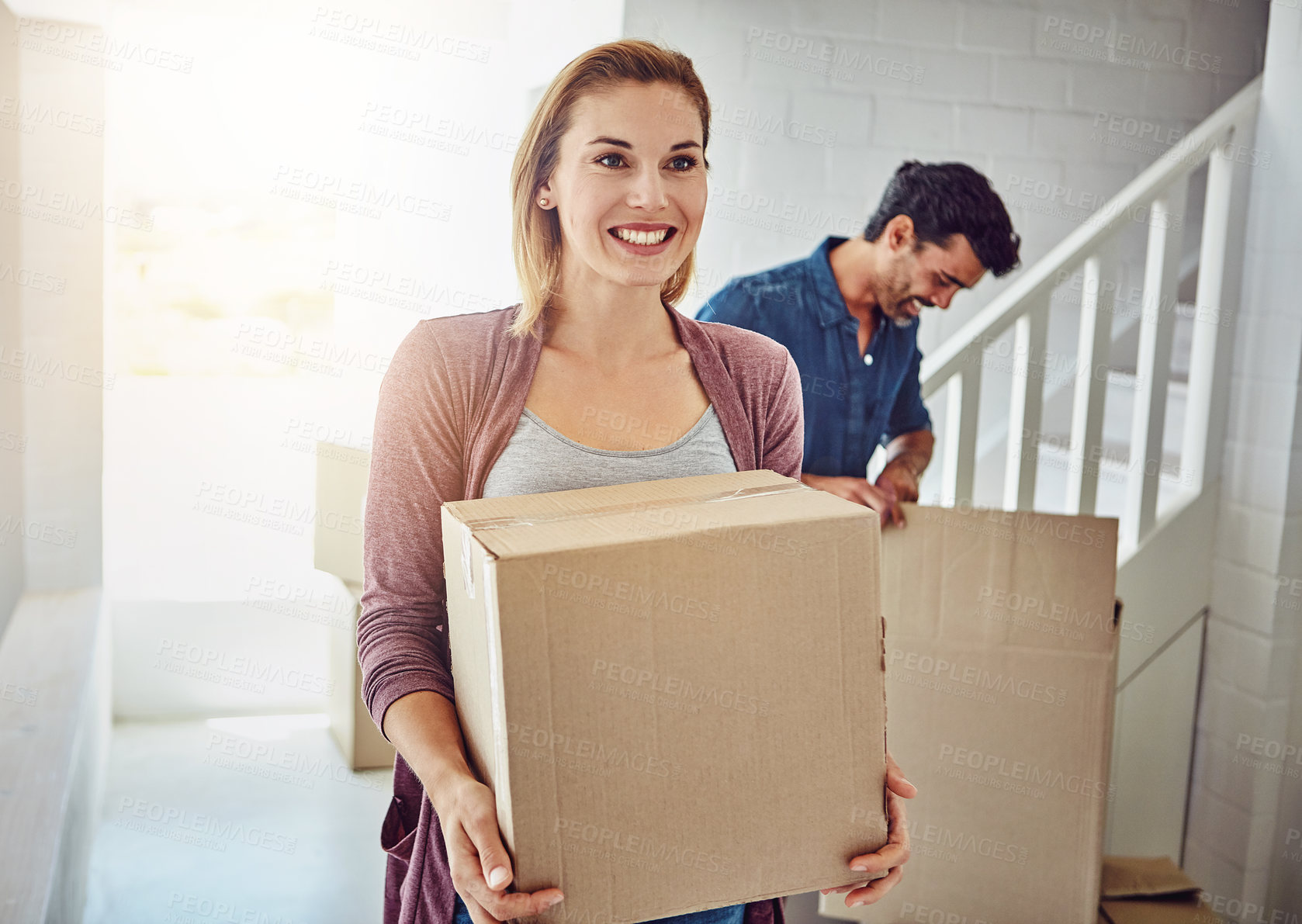 Buy stock photo Couple, moving and new home with boxes, sunshine and happiness with mortgage, real estate and achievement. Apartment, man and woman with package, cardboard and property with lens flare and excited
