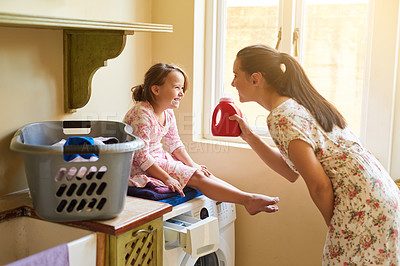 Buy stock photo Shot of a mother and daughter doing laundry together at home