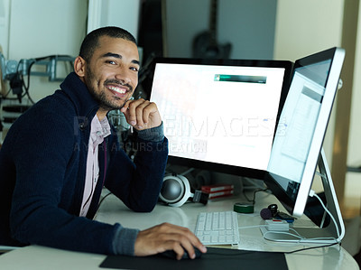 Buy stock photo Portrait of a smiling young man sitting at a desk working on a computer with dual monitors