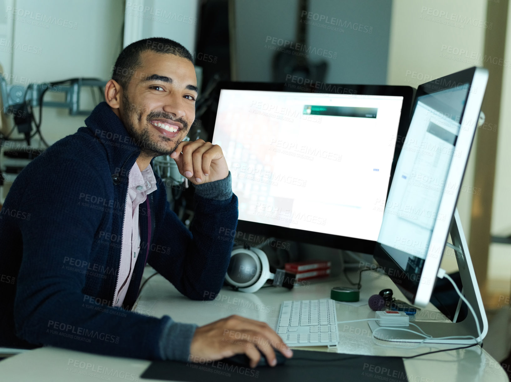 Buy stock photo Portrait of a smiling young man sitting at a desk working on a computer with dual monitors