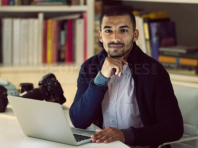Buy stock photo Portrait of a focused young photographer working on a laptop in his home office in the early evening