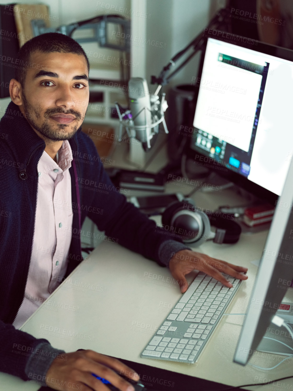 Buy stock photo Portrait of a focused young man sitting at a desk working on a computer with dual monitors