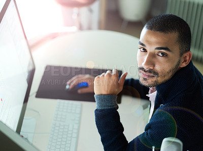 Buy stock photo Portrait of a focused young man sitting at a desk working on a computer with dual monitors