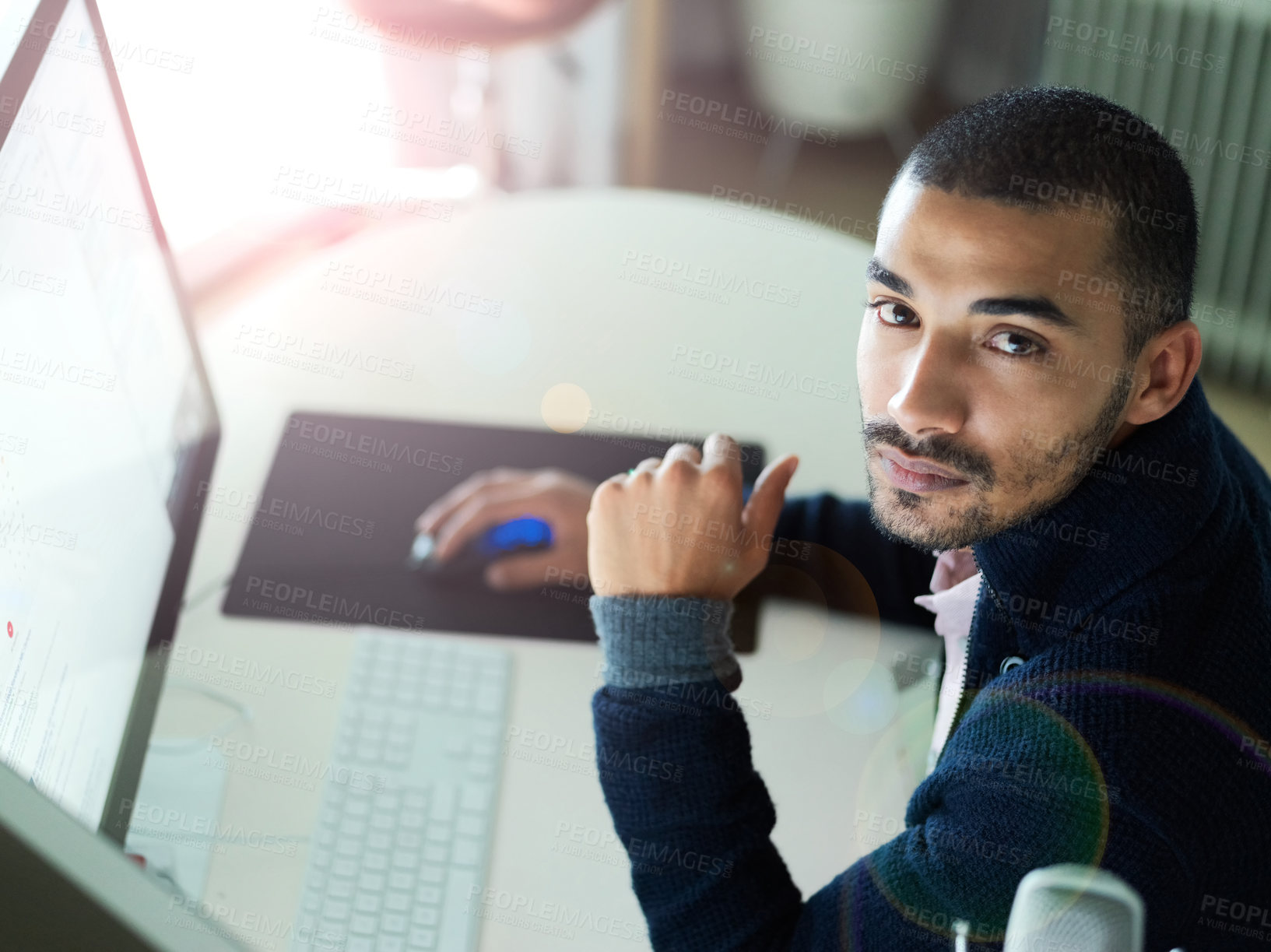 Buy stock photo Portrait of a focused young man sitting at a desk working on a computer with dual monitors