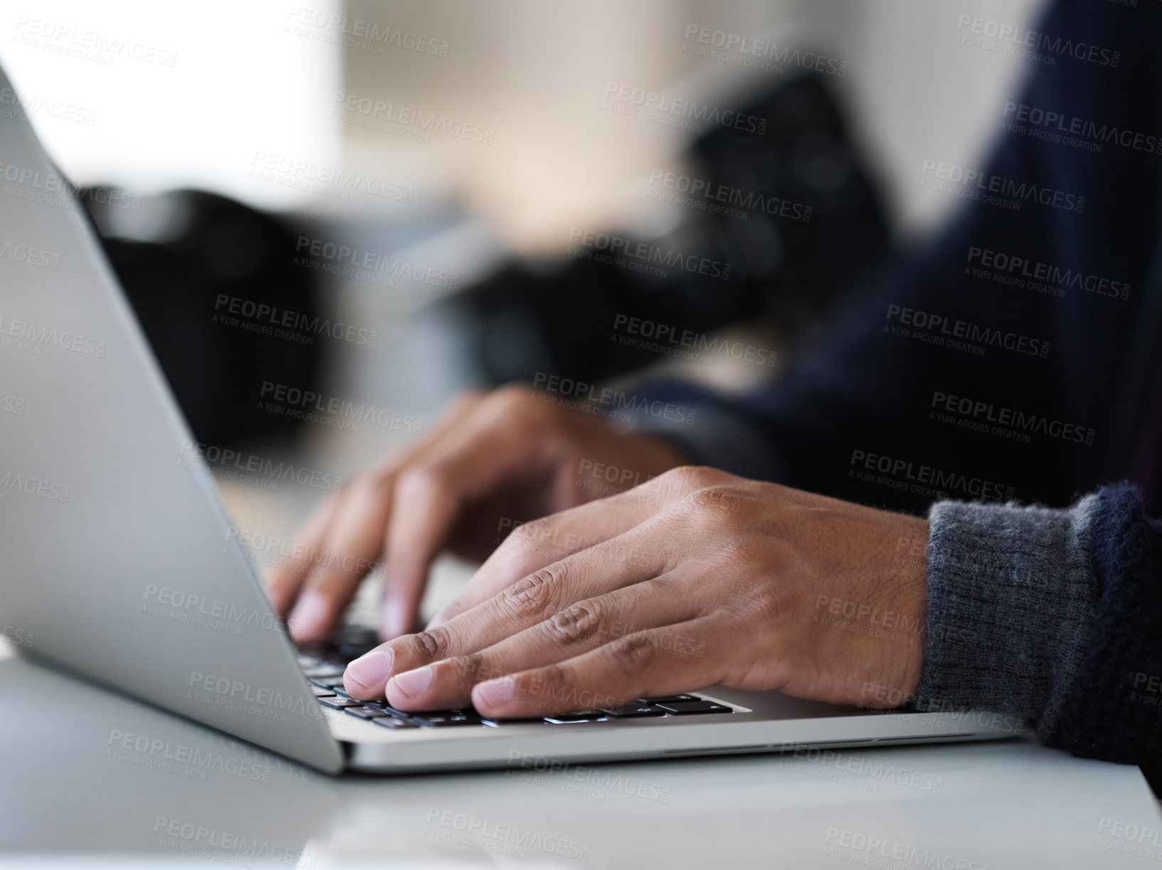 Buy stock photo Cropped closeup shot of an unrecognizable photographer sitting at a table using a laptop