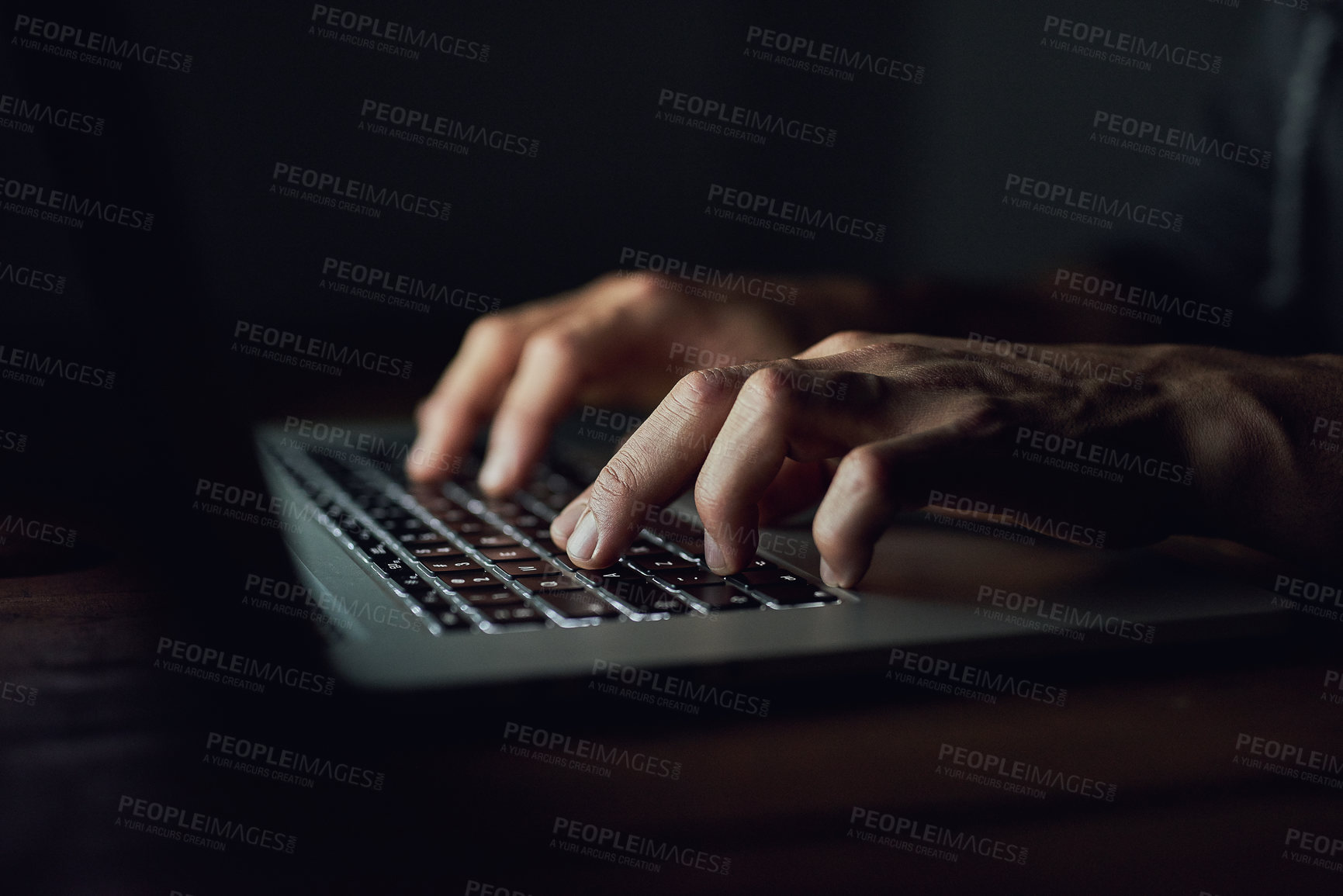 Buy stock photo High angle shot of an unidentifiable man using a laptop late at night