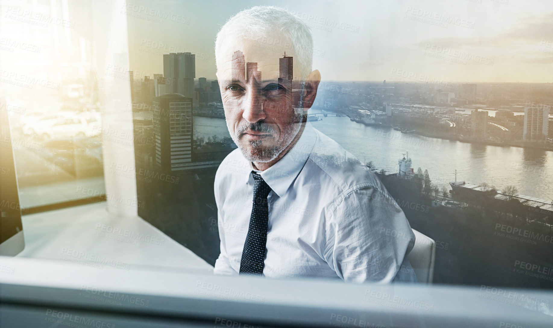 Buy stock photo Shot of a focussed businessman using his computer superimposed over a cityscape