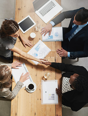 Buy stock photo High angle shot of a group of businesspeople shaking hands during a meeting in an office