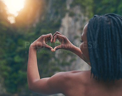 Buy stock photo Rearview shot of a happy young tourist making a heart with her hands against a beautiful landscape
