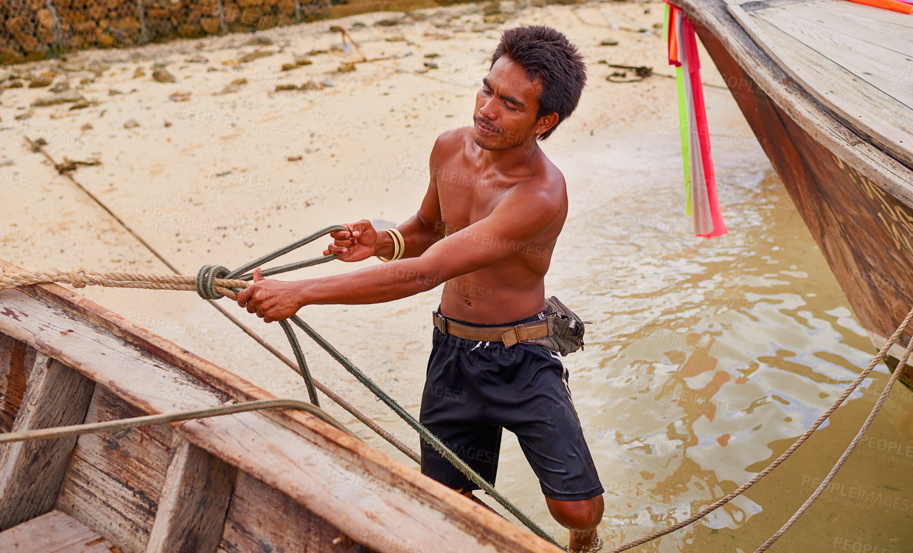 Buy stock photo Shot of a Thai man preparing his boat before heading out to sea