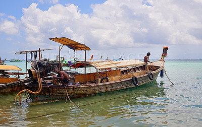 Buy stock photo Shot of two Thai man preparing their boat before heading out to sea
