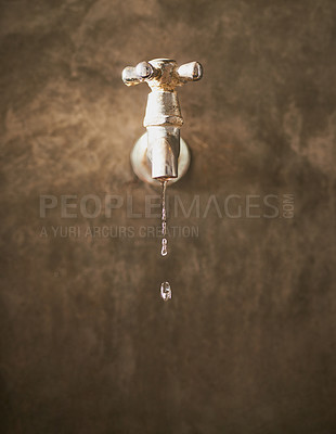 Buy stock photo Closeup view of a metal tap dripping water with copy space.
Old leaky chrome faucet with faulty plumbing in a dirty concrete brown wall wasting water in drought. Saving and conserving water