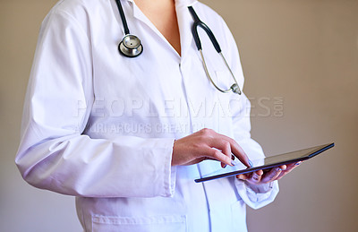 Buy stock photo Cropped shot of an unidentifiable young doctor using a tablet in her office
