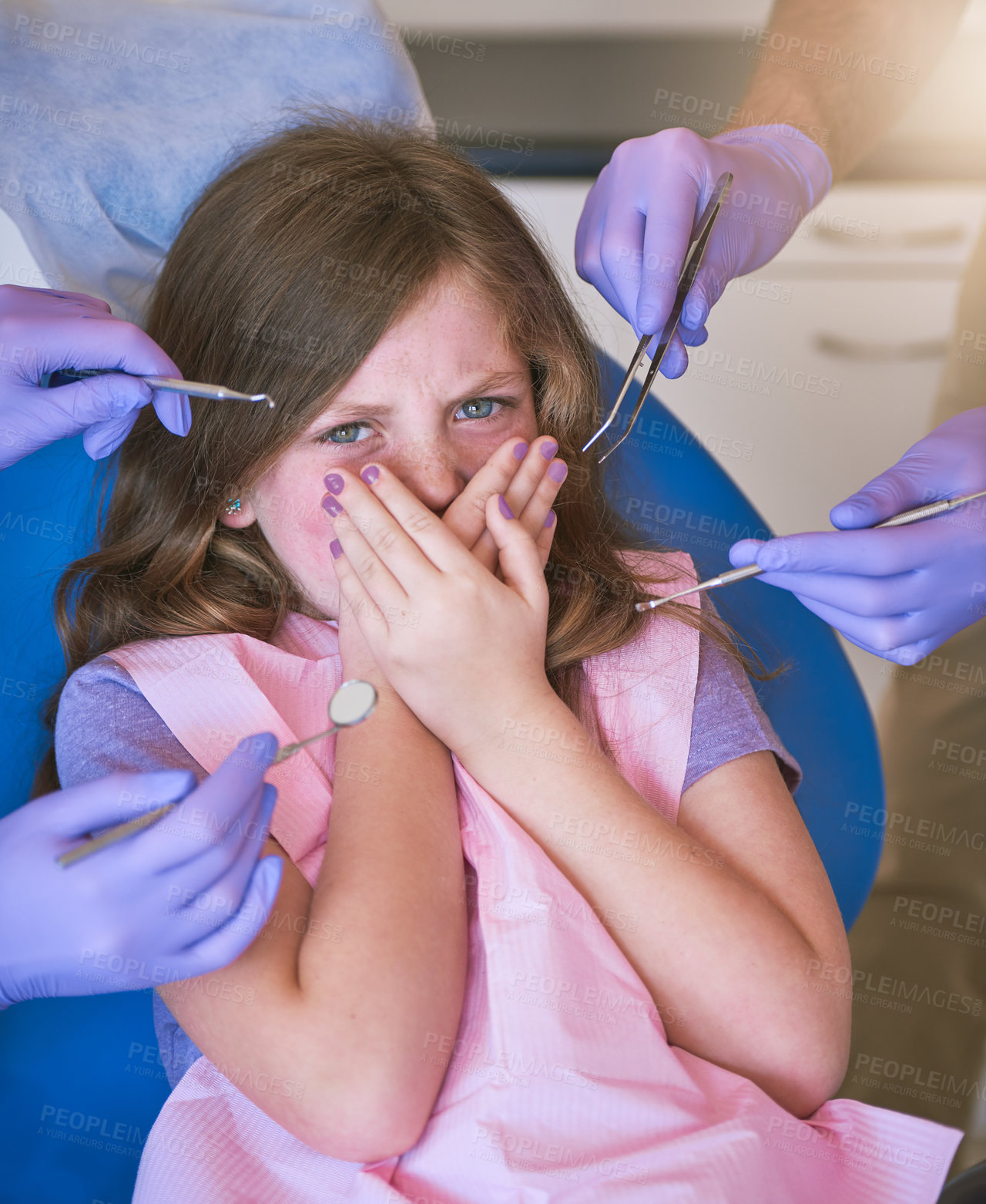 Buy stock photo Shot of a little girl looking terrified as dentists get ready to examine her