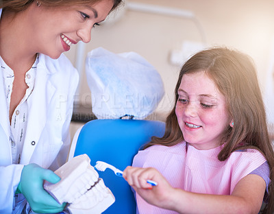 Buy stock photo Cropped shot of a female dentist teaching her young patient how to brush her teeth
