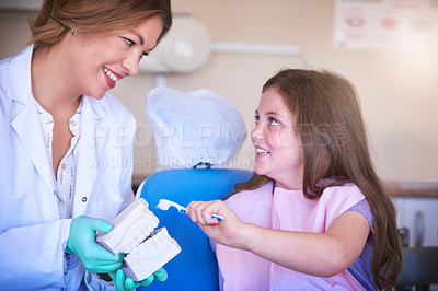 Buy stock photo Dentist, woman and teaching girl for teeth, model or consulting for oral wellness in hospital. Child, orthodontist and 3d mould with toothbrush, cleaning or health with learning for hygiene at clinic