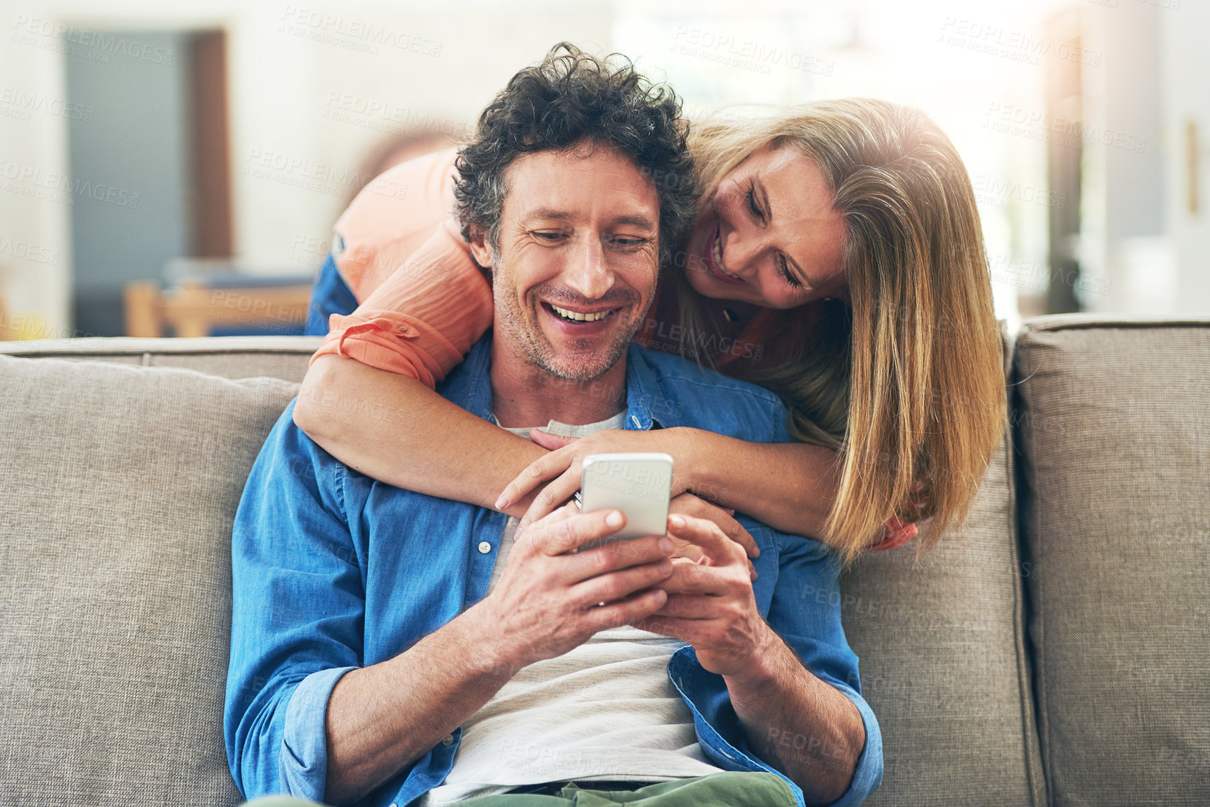 Buy stock photo Mature, couple and hug on sofa with phone for reading online news, social media scroll and embrace in home. People, love and laughing with smartphone for funny meme, bingo or digital gaming on couch
