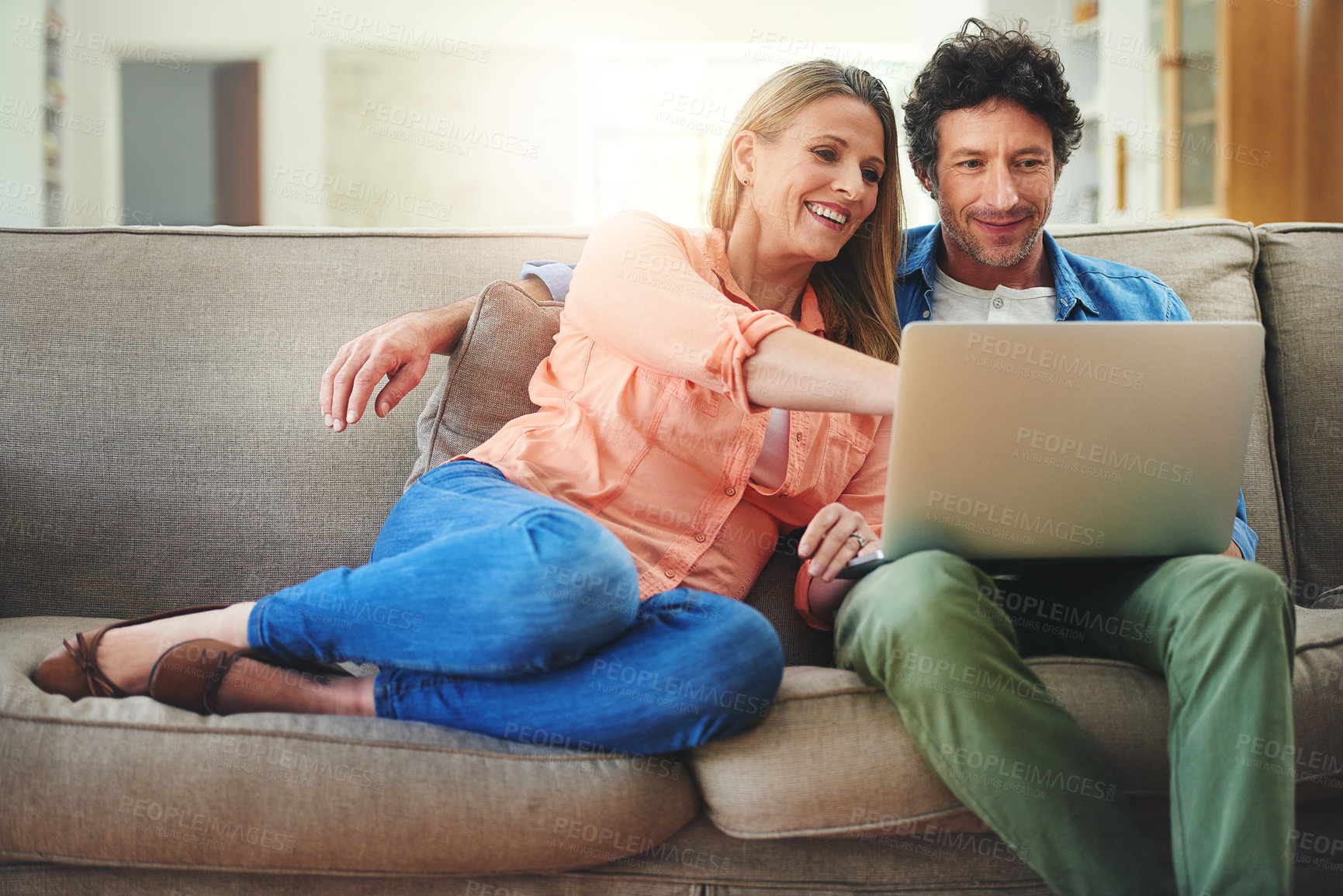 Buy stock photo Shot of a happy mature couple using a laptop together on the sofa at home