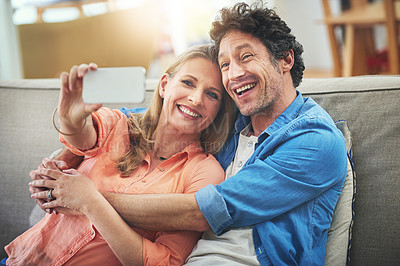 Buy stock photo Shot of a happy mature couple taking a selfie together on the sofa at home