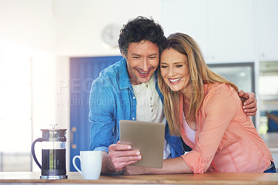 Buy stock photo Shot of a happy mature couple using a digital tablet together in the kitchen at home