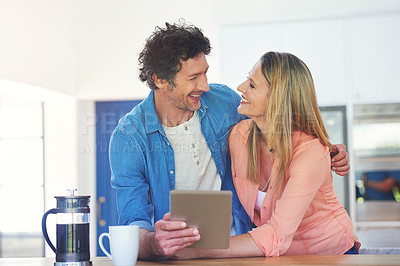 Buy stock photo Shot of a happy mature couple using a digital tablet together in the kitchen at home