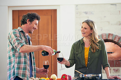 Buy stock photo Shot of a happy mature couple enjoying some wine while preparing a meal together at home