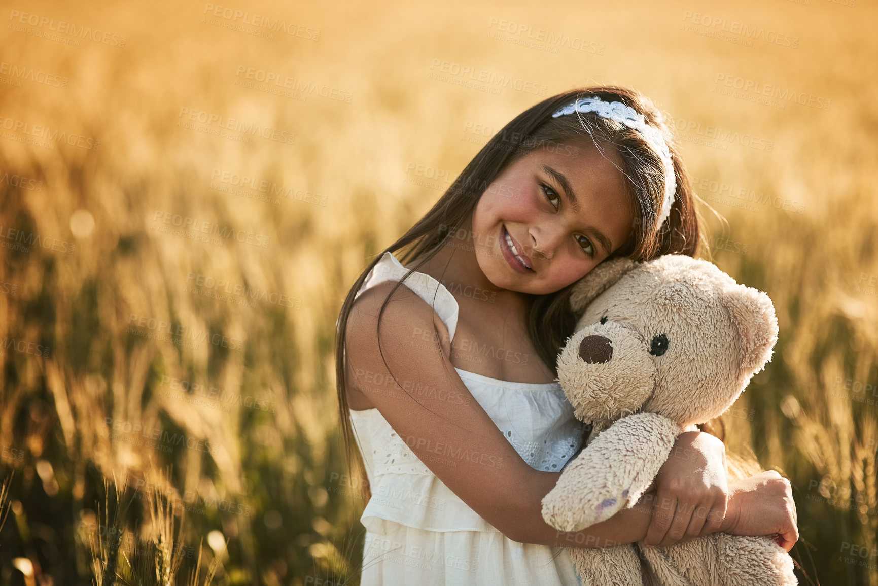 Buy stock photo Portrait of a cute little girl playing with her teddybear in a cornfield