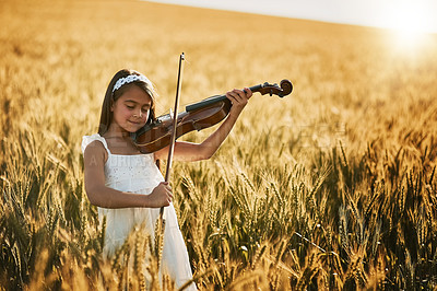 Buy stock photo Portrait of a cute little girl playing the violin while standing in a cornfield