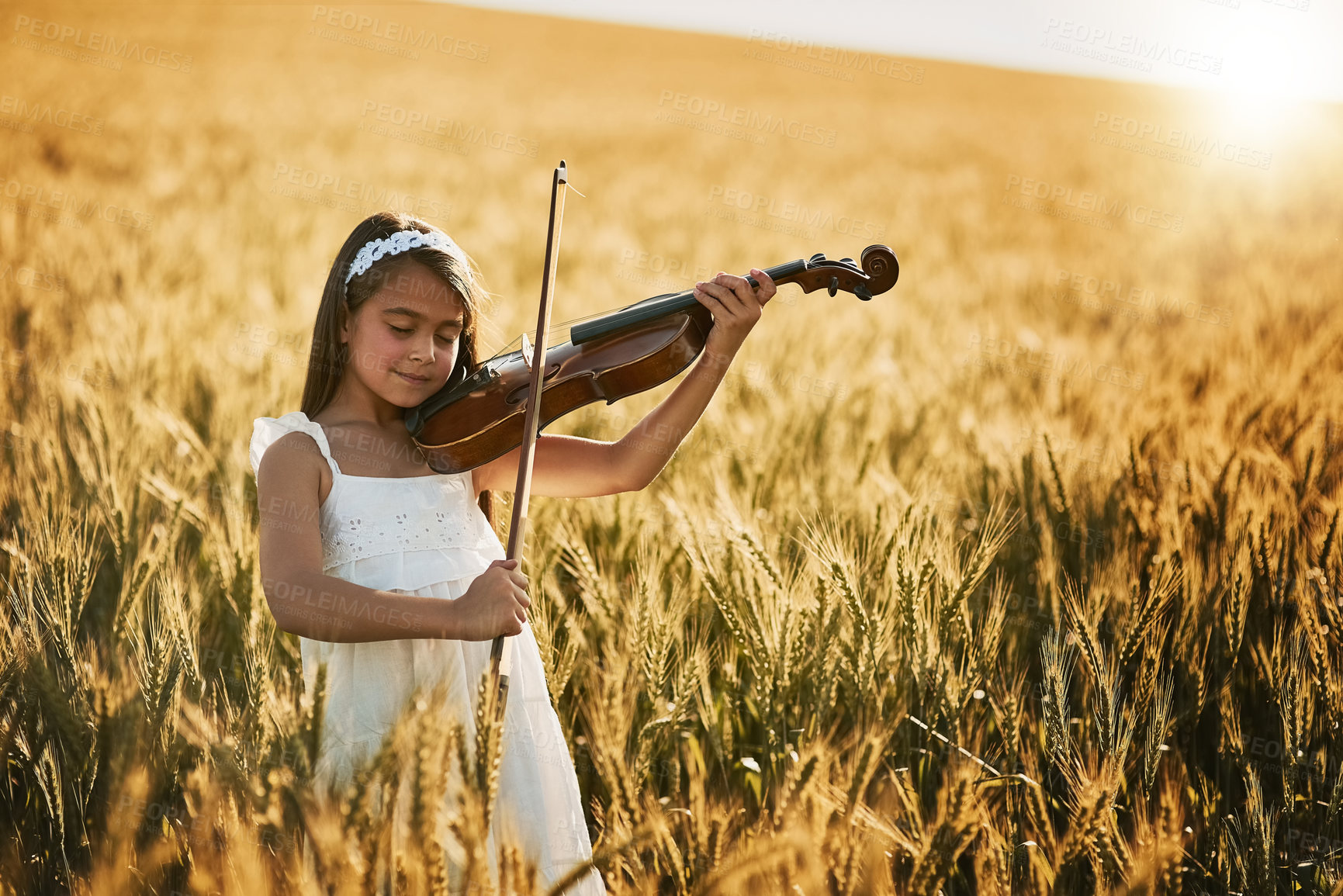 Buy stock photo Portrait of a cute little girl playing the violin while standing in a cornfield